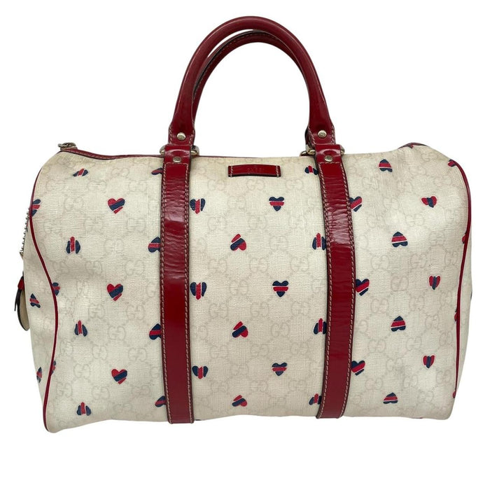 Gucci cream duffel bag with red monogram heart print and logo detailing.