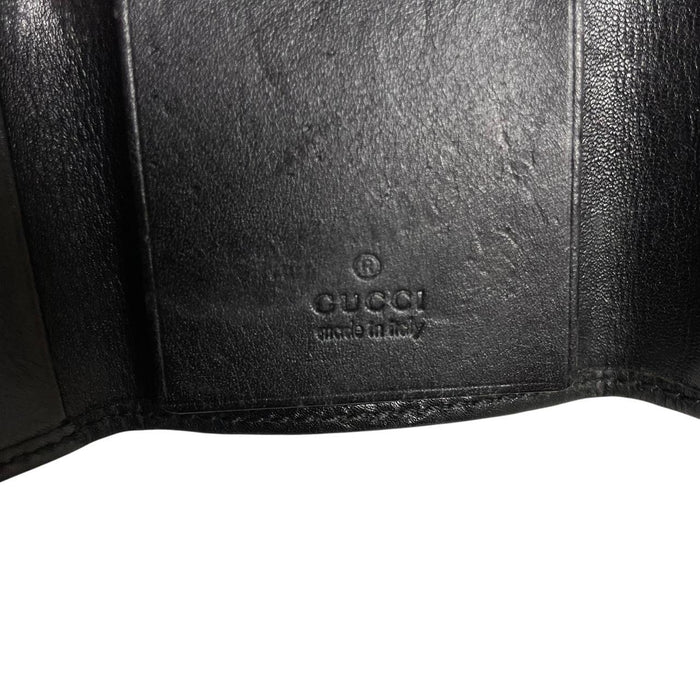 Gucci black leather key case featuring GG monogram pattern and scuffed details.