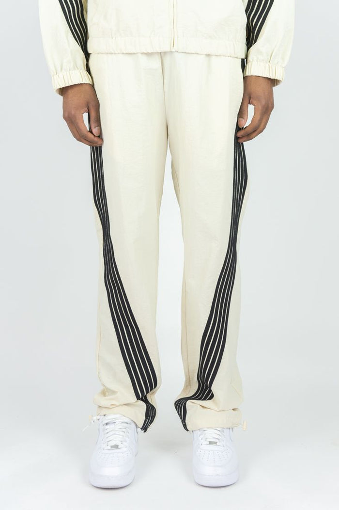 Rebel Minds Bent Stripes cream nylon sweatpants with a relaxed fit and striped design, shown on a plain background.