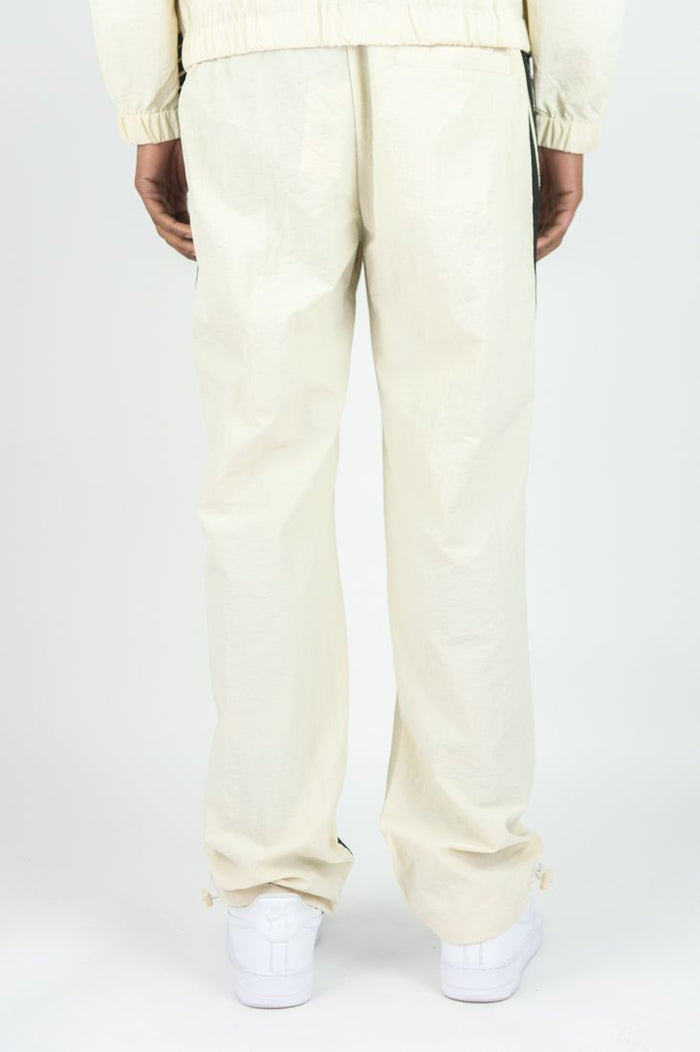 Rebel Minds Bent Stripes nylon sweatpants in cream, featuring a relaxed fit and striped design, shown on a model.