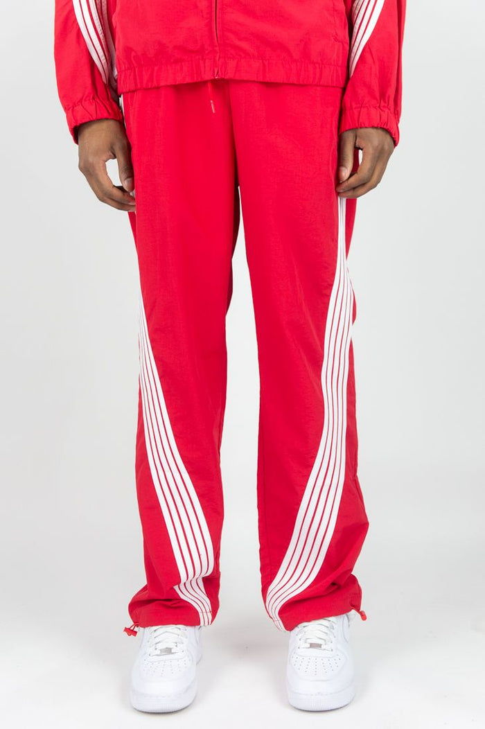 Red Rebel Minds Bent Stripes nylon sweatpants with a relaxed fit and elastic waistband, featuring bold stripe details.