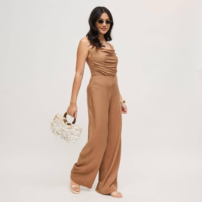 Model carrying the Scarlett Evening Bag by its polished wood ring handles, highlighting the layered shell disc exterior and sculptural silhouette.
