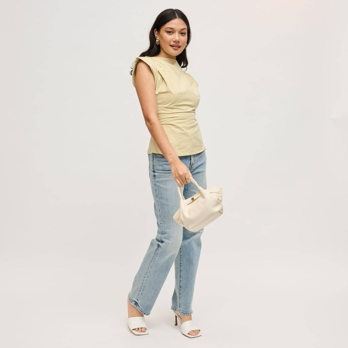 Model carrying the Selena Crossbody in cream by its rolled top handles, featuring soft vegan leather, a gathered silhouette, and polished gold-tone hardware.