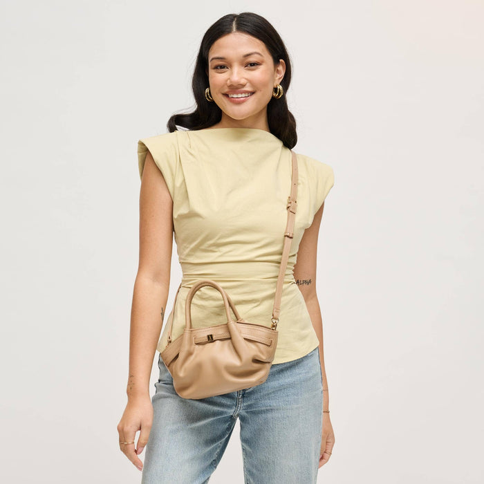 Model wearing the Selena Crossbody as a crossbody bag in taupe vegan leather with an adjustable strap and modern gathered mini satchel design.