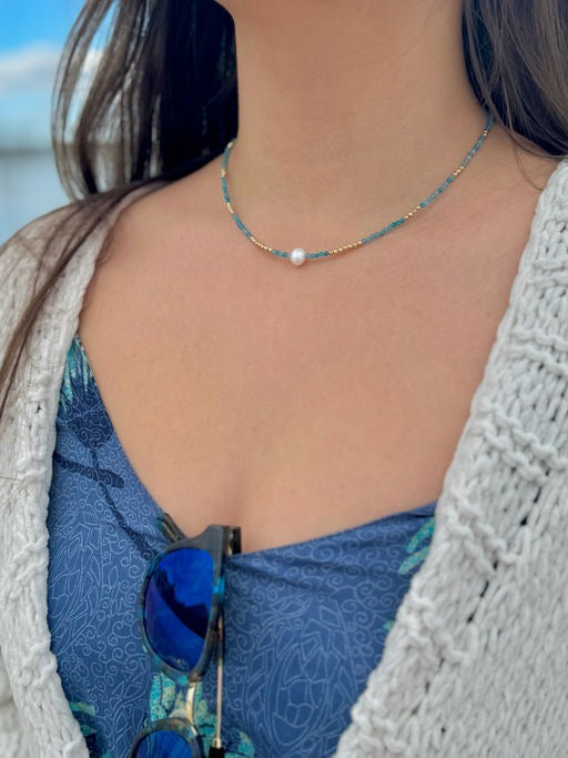 Model wearing Sera Apatite Necklace, a delicate blue apatite beaded necklace with gold accents and center pearl.