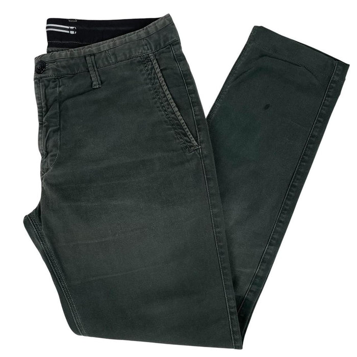 Stone Island green slim fit cotton trousers with logo patch and faded details.