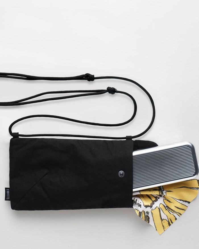 Black Sunnies Sling holding a tin and lens cloth, showing capacity