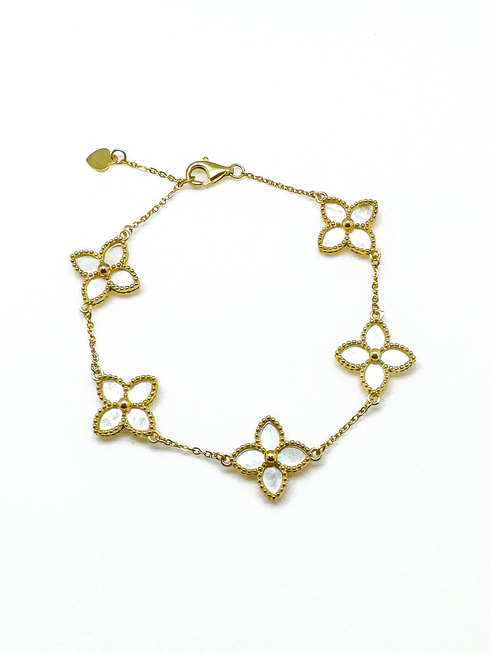 Gold bracelet with floral designs on a white background