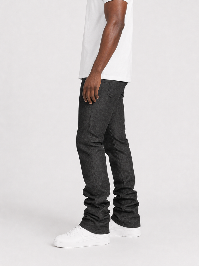 Taker Raw Fabric Stack Denim in Raw Black, showcasing folded raw black denim jeans with visible stitching and texture.