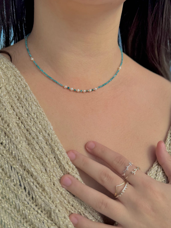 Model wearing Tessa Apatite and Miyuki Bead Necklace featuring teal apatite beads, Miyuki accents, and pearl details at the collarbone.