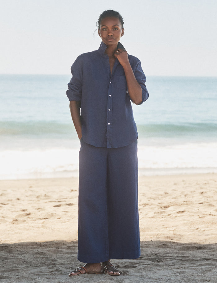 Person wearing a blue outfit standing on a beach with ocean in the background