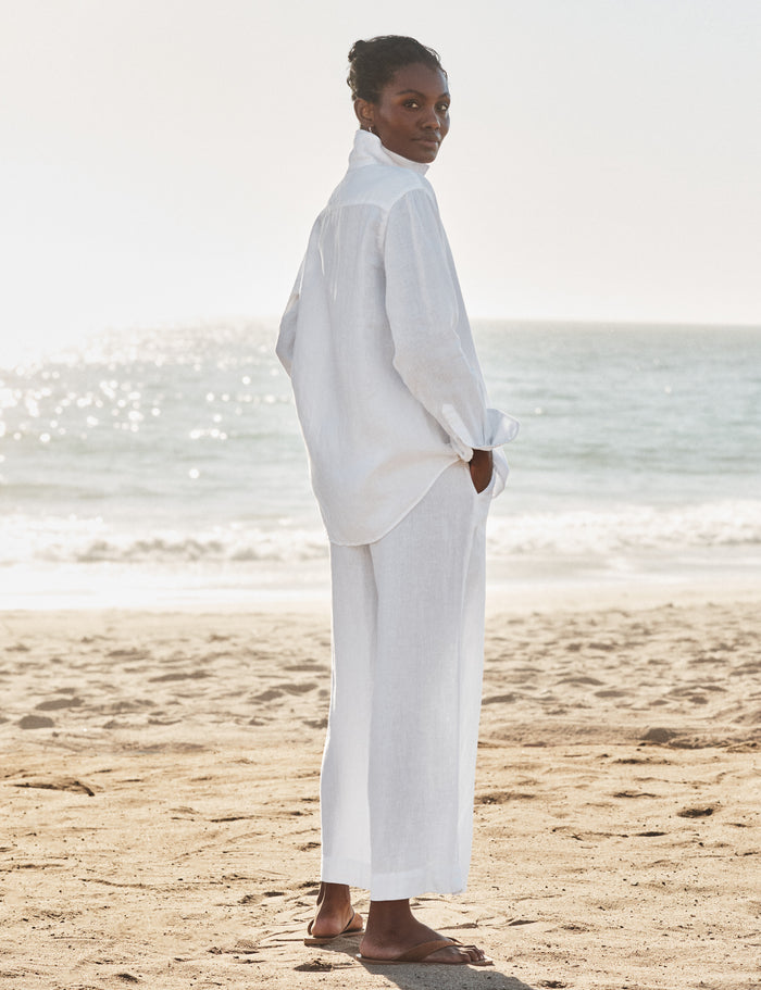 Person wearing a white outfit standing on a beach with ocean in the background