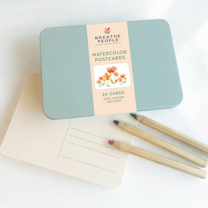 Breathe People watercolor postcards in a tin with a pen on a white background