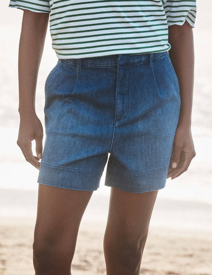 Person wearing blue denim shorts on a beach