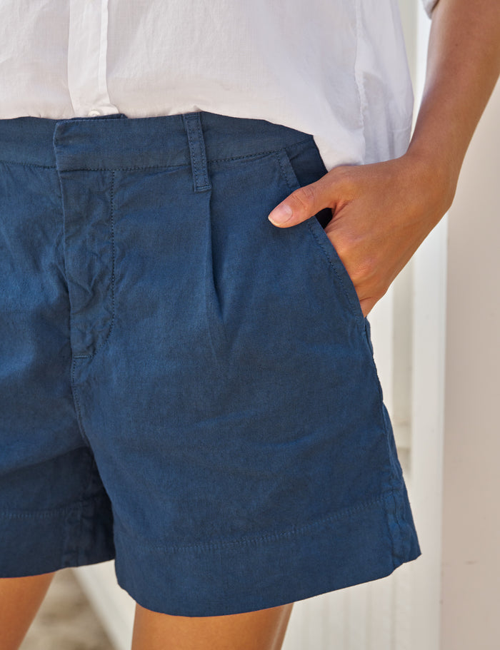 Person wearing blue shorts with a neutral background