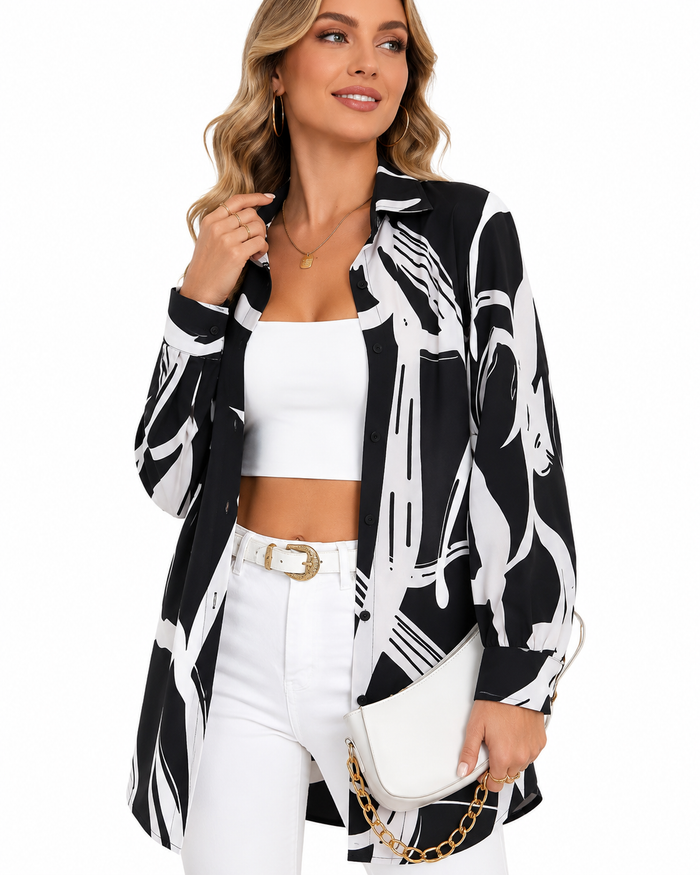 A woman models a black and white abstract print blazer over a white crop top and white pants, holding a white handbag with a gold chain strap against a plain white background.