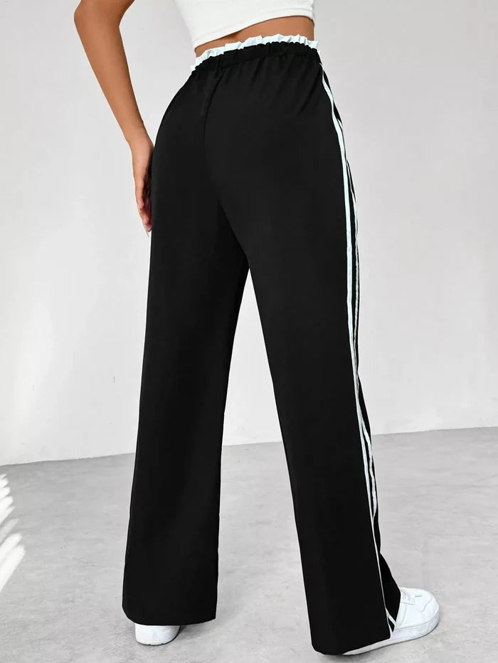 Black wide-leg pants with white stripes on a gray background
